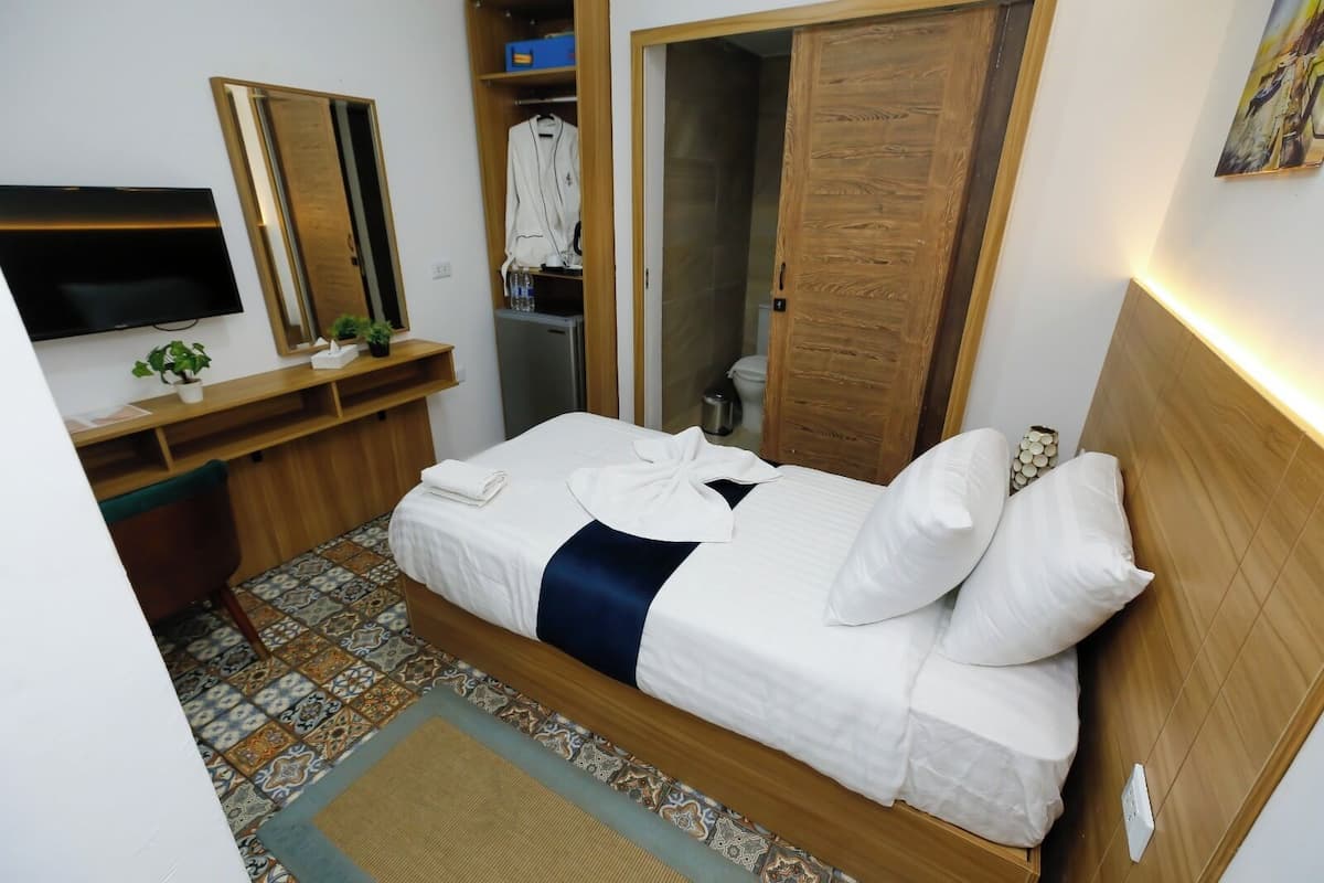 A neatly arranged hotel room with a bed, a TV, a desk, and a wardrobe.
