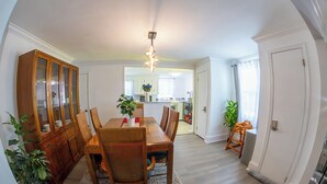 A dining area with a wooden table, chairs, and a cabinet. There is a rug on the floor, and a plant is visible. - Family Home-Sleeps 8-Spacious 3BR-Free Parking-8 Min to PHL (Sharon Hill)