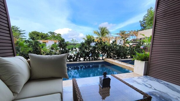A balcony with a pool, a wicker table, and a sofa.