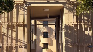 A gated entrance to a building with a modern design, featuring a central door and a staircase leading to an upper level.