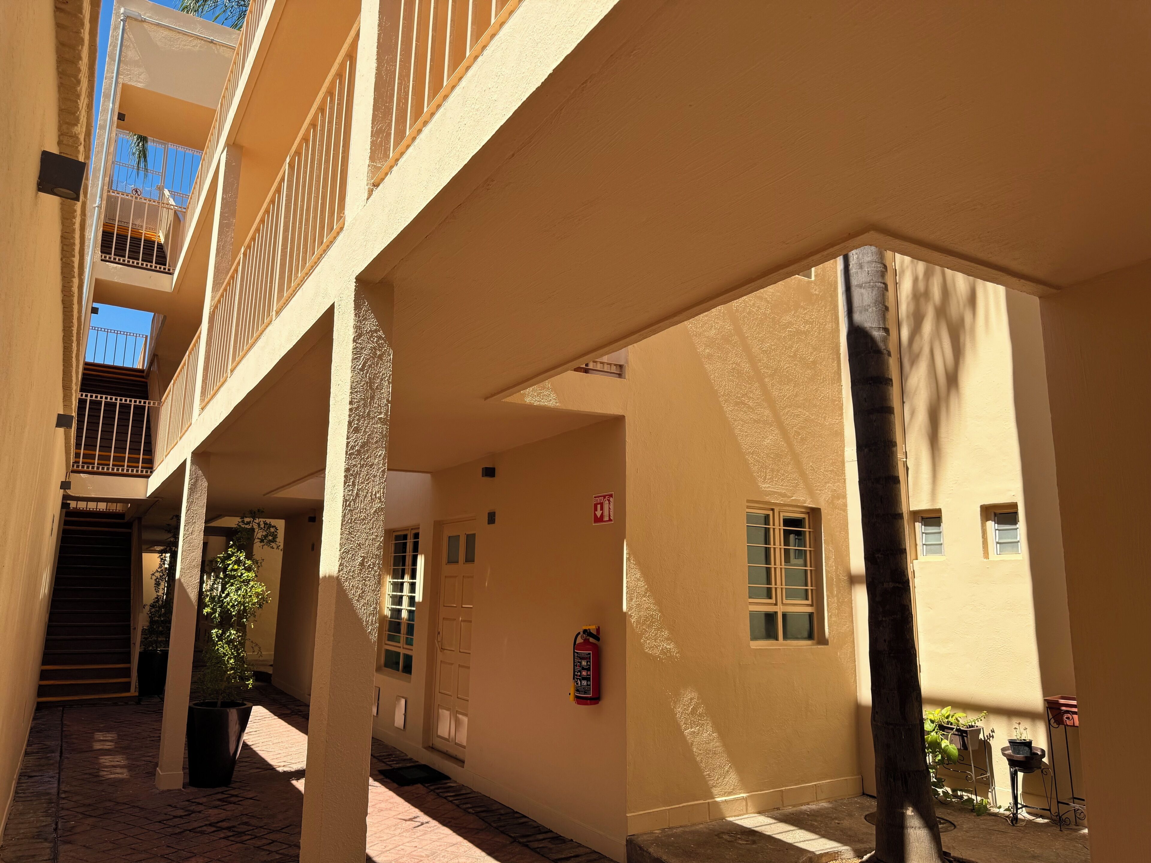 Un edificio con varios balcones, un extintor y plantas en macetas.