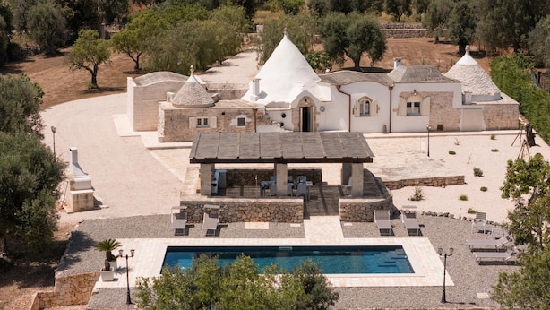 Μια βίλα με πισίνα, πέτρινη αρχιτεκτονική και έναν κήπο.