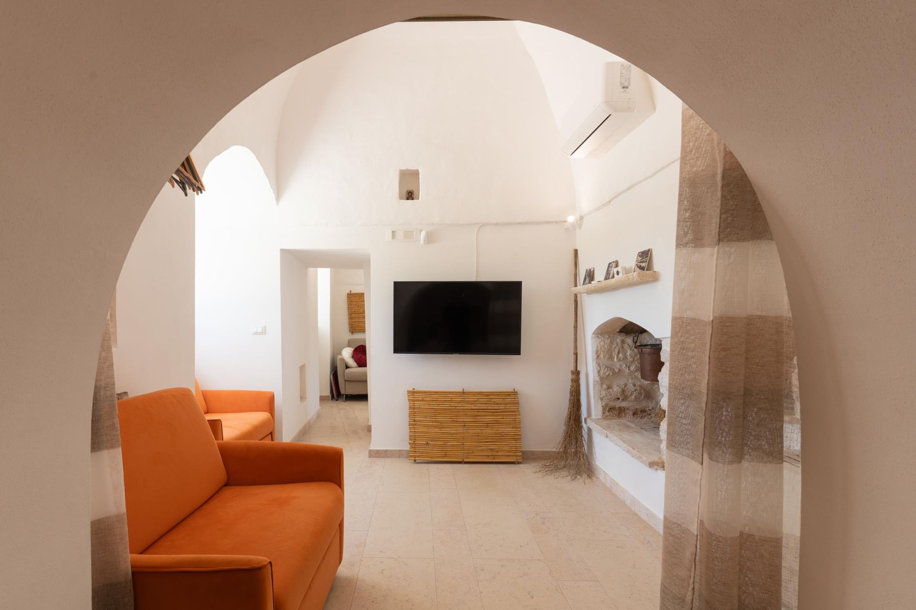 A modern living room with a large flat-screen TV, orange sofas, and a stone fireplace.