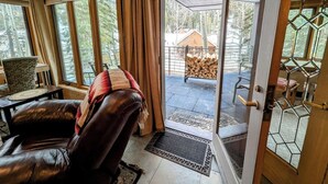 A cozy living room with a leather sofa, a wooden coffee table, and a view of a wooden deck and trees outside. - Chateaux Dumont 2724 (Keystone)