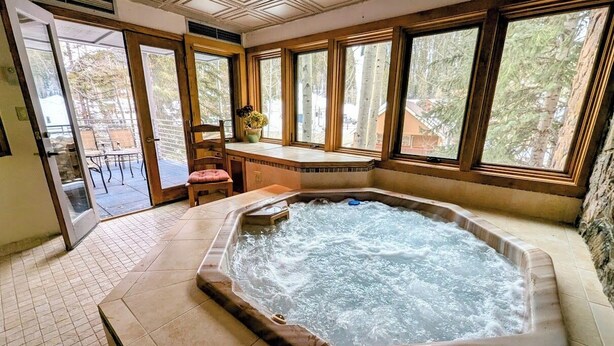 A hot tub in a room with large windows, a door leading outside, and a tiled floor. - Chateaux Dumont 2724 (Keystone)