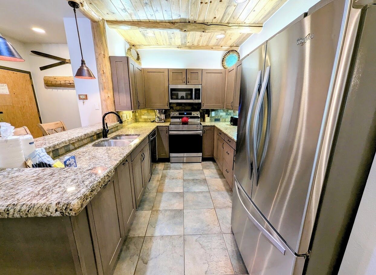 Una cocina con encimeras de granito, electrodomésticos de acero inoxidable y armarios de madera.