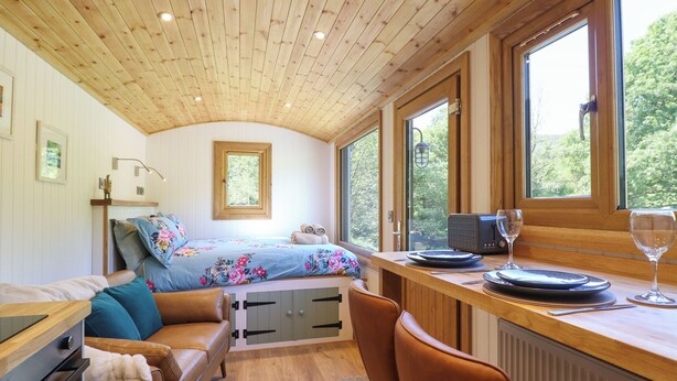 Ein gemütliches Blockhaus-Interieur mit einem Bett, einem Essbereich und Blick ins Freie.