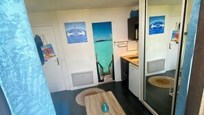 A compact room with a small table, a door with a view of the sea, and a wall with a painting. - 2-person studio with sea view and pool in Porticcio residence. Corsica. (Grosseto-Prugna)