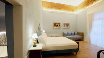 Una habitación de hotel con cama, mesita de noche, lámpara y un pequeño sofá.
