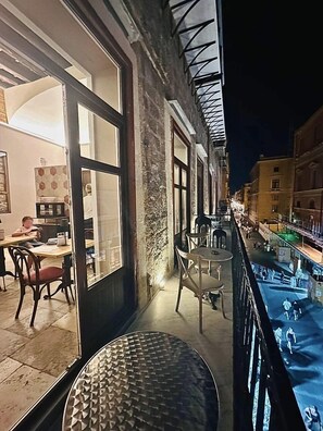 A balcony with a view of a street at night. There are tables and chairs on the balcony. - Heritage Collection Palermo B&B (Palermo)