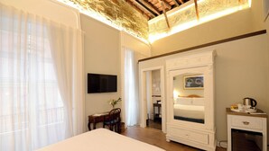 Habitación de hotel con una cama grande, un escritorio con silla, televisor, armario y una pequeña kitchenette.