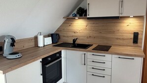 A modern kitchen with white cabinets, a wooden countertop, a built-in oven, and a sink. - Vacation home Küstennebel directly by the sea (Butjadingen)