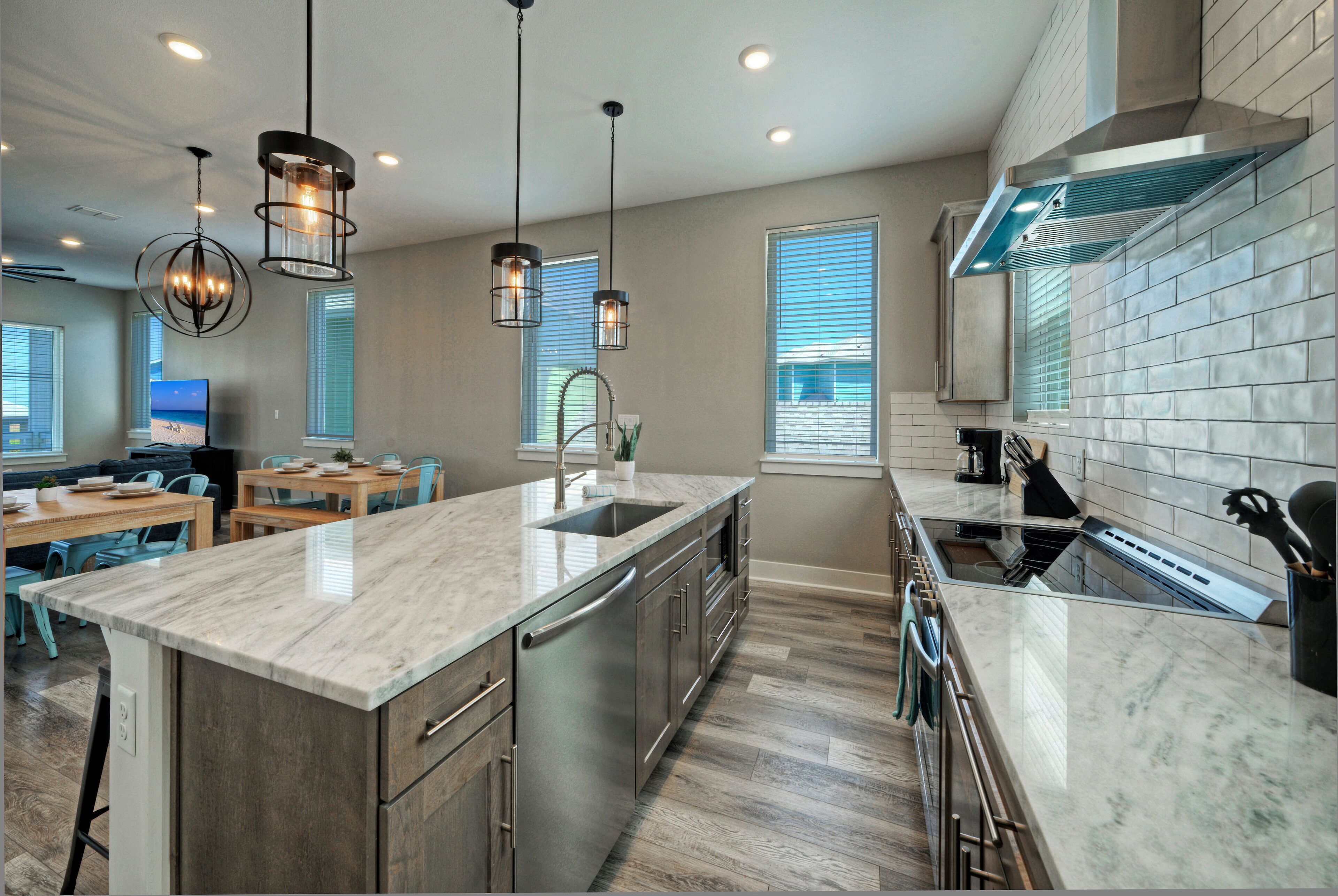 A modern kitchen with a large island, stainless steel appliances, and pendant lighting.