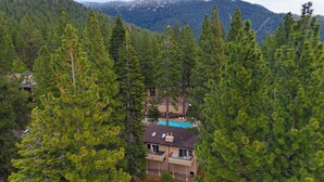 A house surrounded by tall pine trees with a mountain in the background.