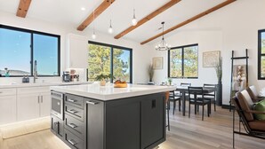 Una cocina moderna con una isla grande, vigas de madera y ventanas amplias.