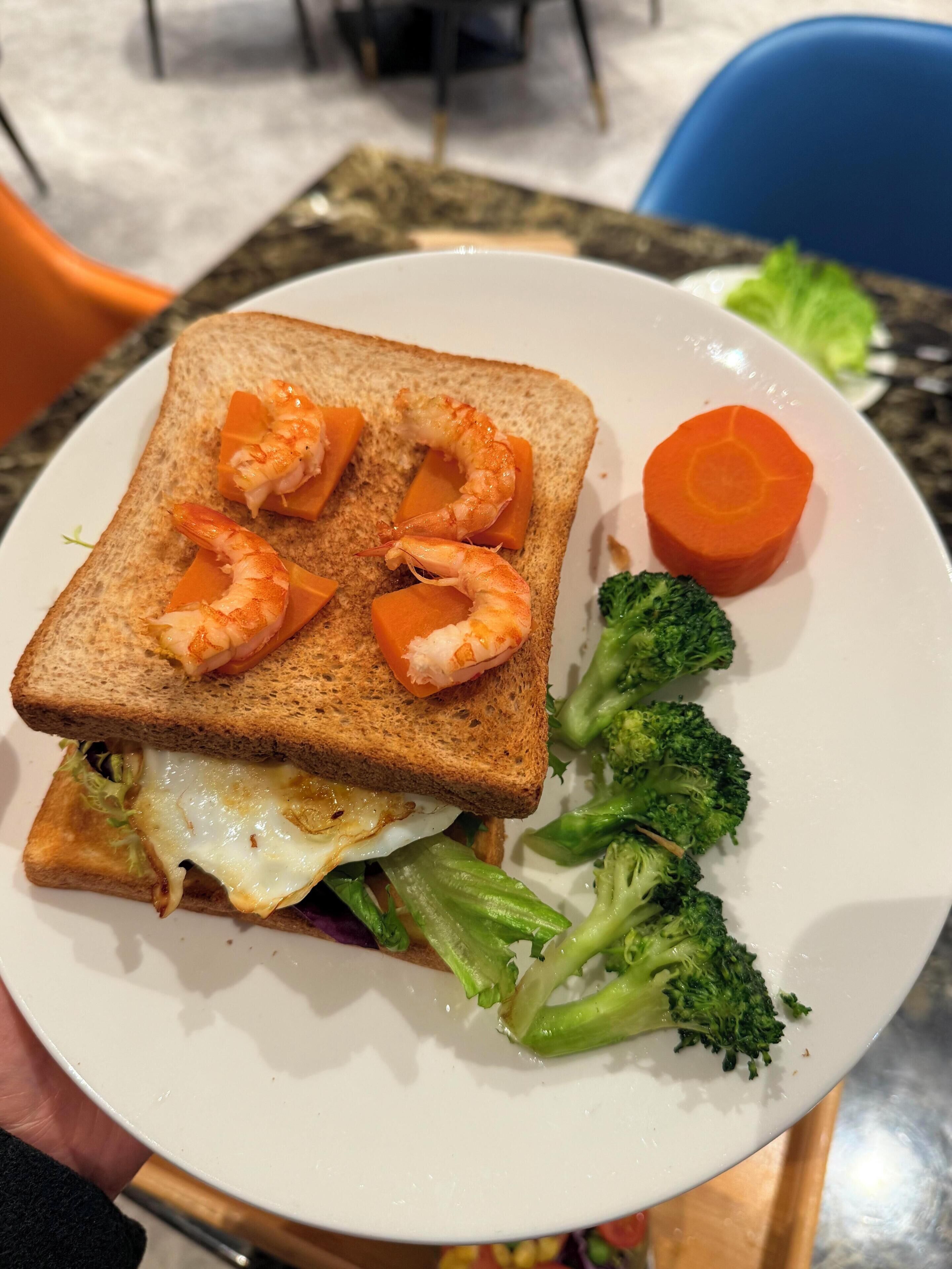 A sandwich with shrimp, egg, and vegetables on a plate.