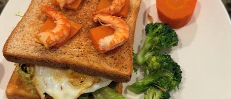 A sandwich with shrimp, egg, and vegetables on a plate.