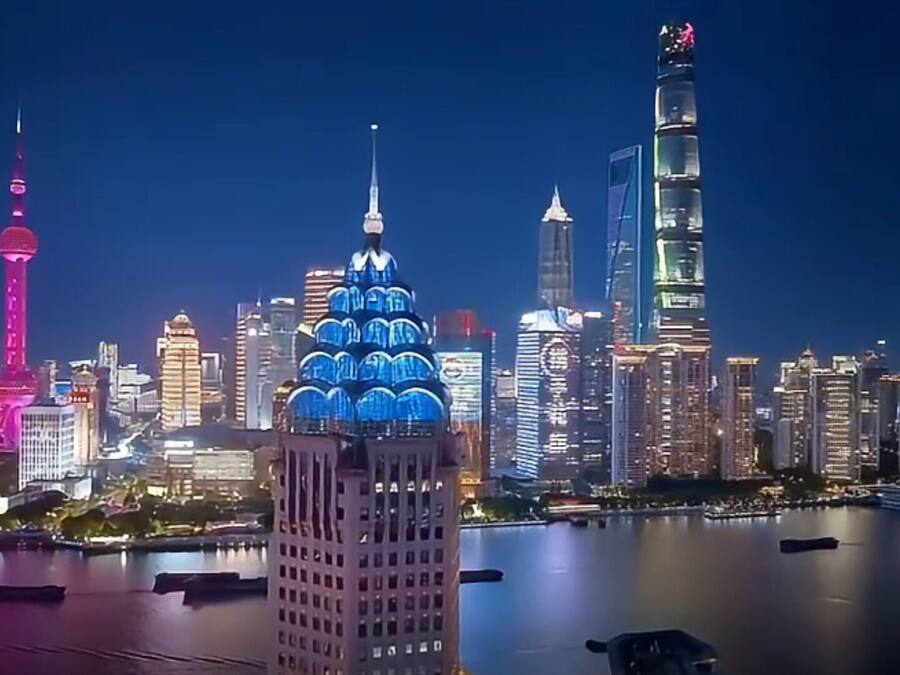 Un horizonte urbano nocturno con edificios destacados, incluyendo una torre con aguja y un rascacielos con un diseño en capas único.