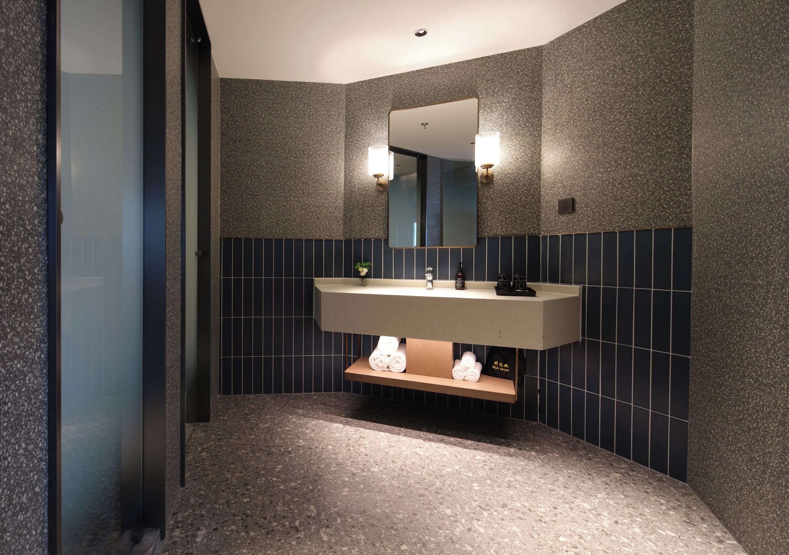 A modern bathroom with a granite countertop, a large mirror, and a towel rack.
