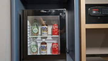 Un minibar con una bottiglia di Chang Soja Water, una bottiglia di whisky Suntory e due lattine di Coca-Cola.