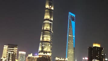 Un horizonte urbano nocturno con edificios iluminados, incluyendo una torre destacada con la punta iluminada en azul.