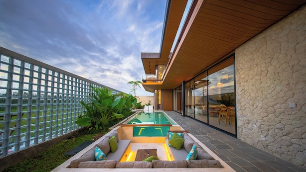 A modern outdoor pool area with a geometric design, surrounded by a stone wall and a wooden ceiling.