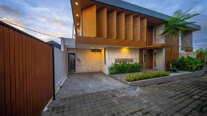 A modern house with a stone facade, a wooden fence, and a paved driveway.