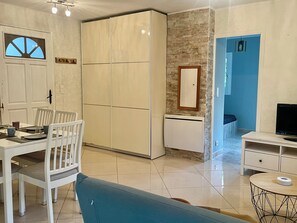 Een moderne woonkamer met een eethoek, een grote garderobe, een ingebouwde heater en een televisie.