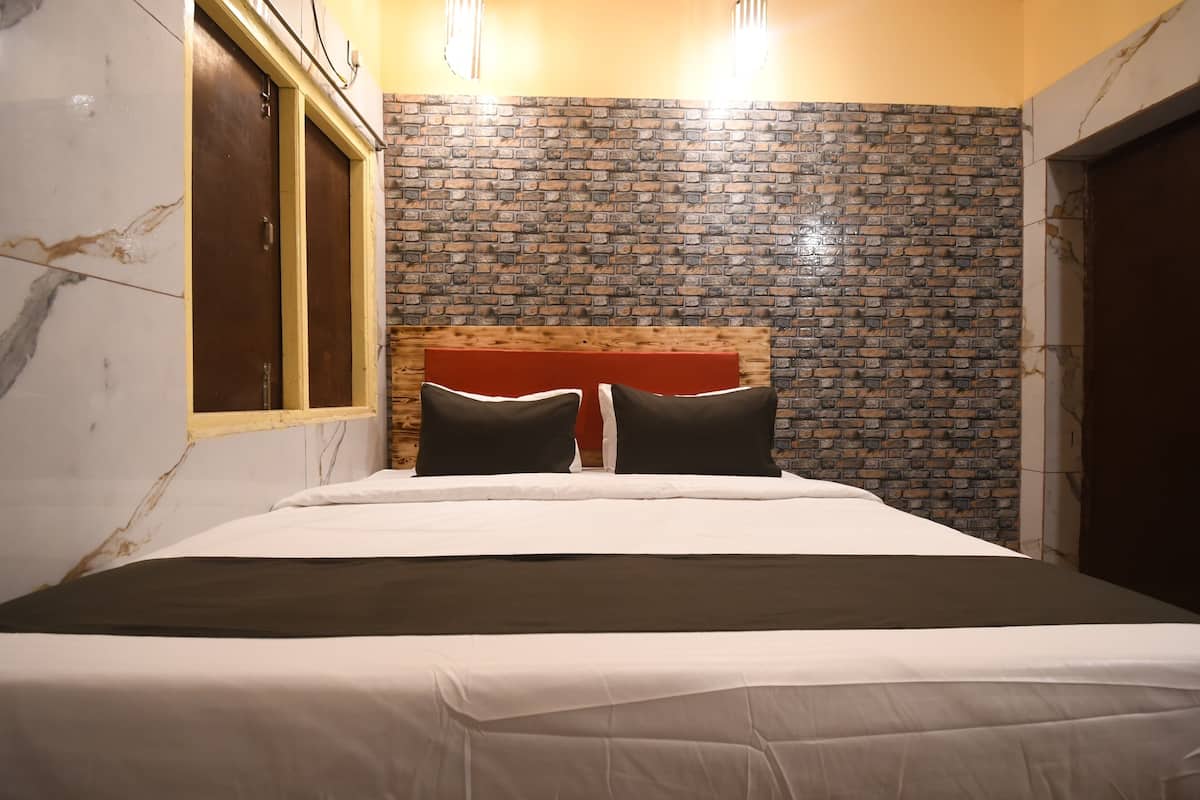 A hotel room with a bed, wooden headboard, brick-patterned wall, and a window with a wooden frame.