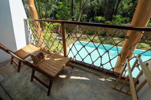 A wooden deck with a rope barrier, a pool, and lush greenery.