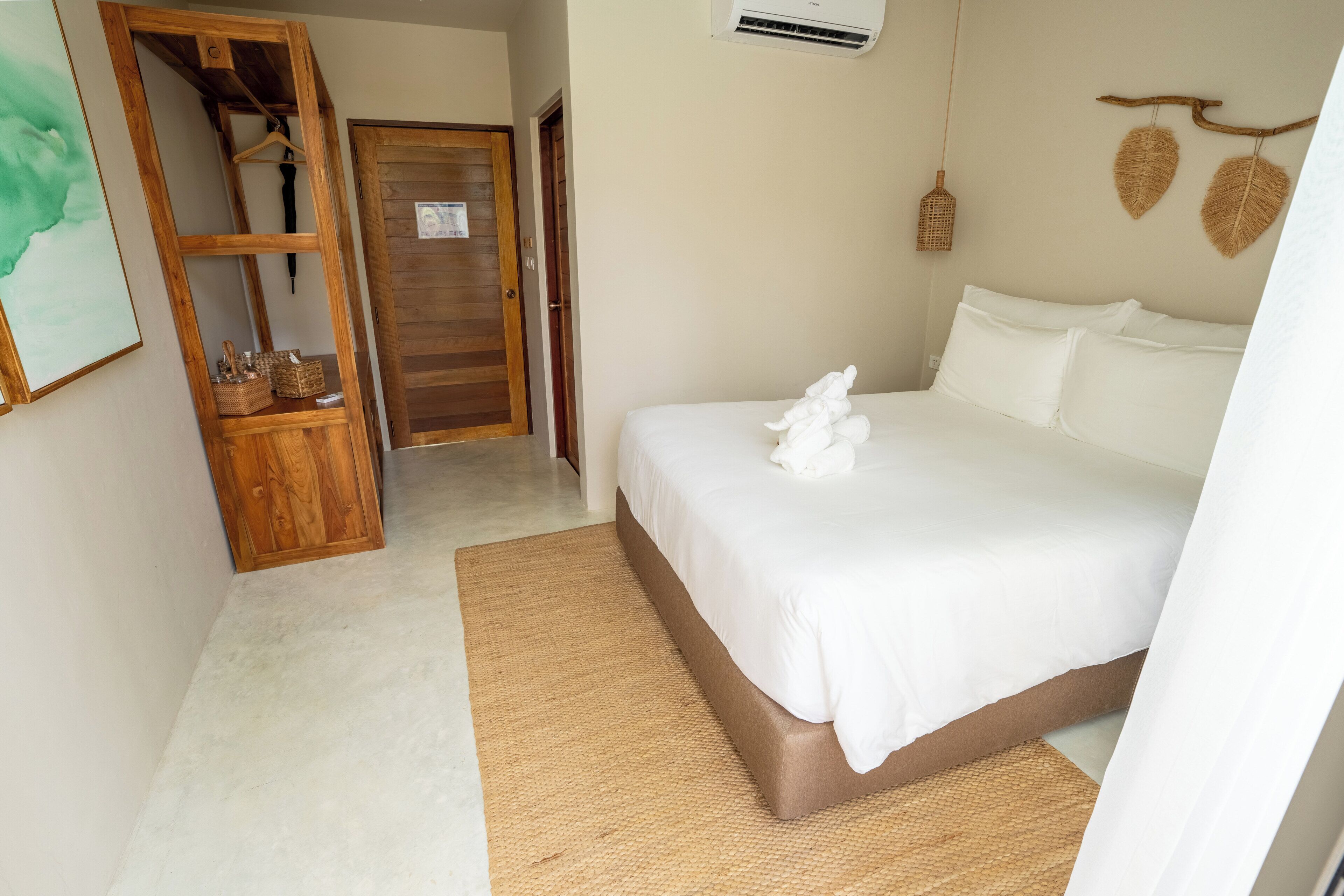 A bedroom with a bed, a wooden wardrobe, a hanging basket, and a wall-mounted air conditioner.