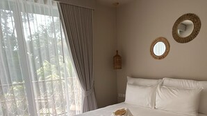 Ein ordentlich bezogenes Bett mit weißen Leinentüchern, einem braunen Kopfteil und einem gewebten Teppich auf dem Boden.
