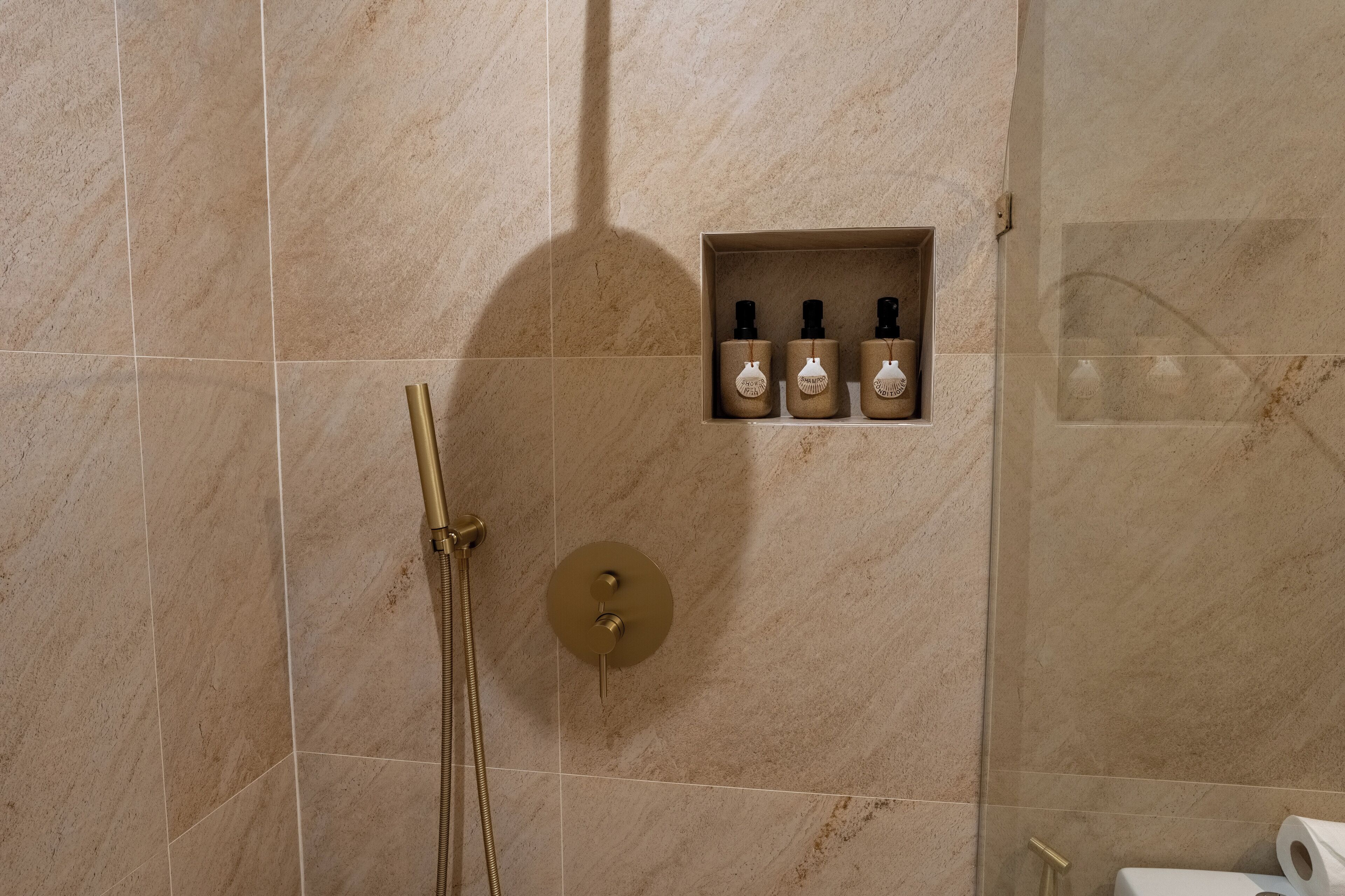 Ein Badezimmer mit Dusche, Handtuchhalter und Ablage für Toilettenartikel.
