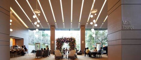 A spacious lounge area with modern lighting, a central floral arch, and a polished floor.