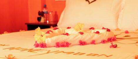 A bed with a heart-shaped pillow and a floral arrangement.