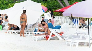 A beach with white lounge chairs and umbrellas. - SEASUNBEACH MAAFUSHI (Maafushi)