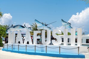 Une grande enseigne portant le mot « MAAFUSHI » et ornée de sculptures de poissons décoratives.