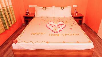 A bed with "Happy Honeymoon" written on the bedspread, surrounded by heart-shaped flower arrangements.