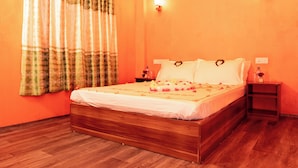 A bedroom with a wooden bed, a nightstand, a lamp, and a wall-mounted light fixture. - SEASUNBEACH MAAFUSHI (Maafushi)