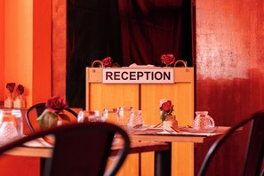 Un espace d’accueil avec une enseigne en bois portant l’inscription « RÉCEPTION » et une table agrémentée d’un vase de roses.