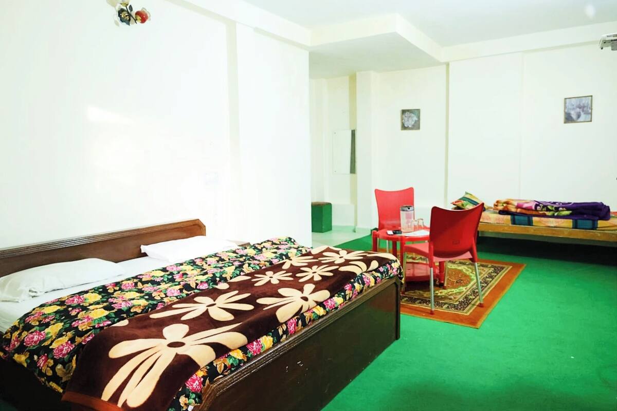 A room with a bed, a red chair, and a small table with items on it.
