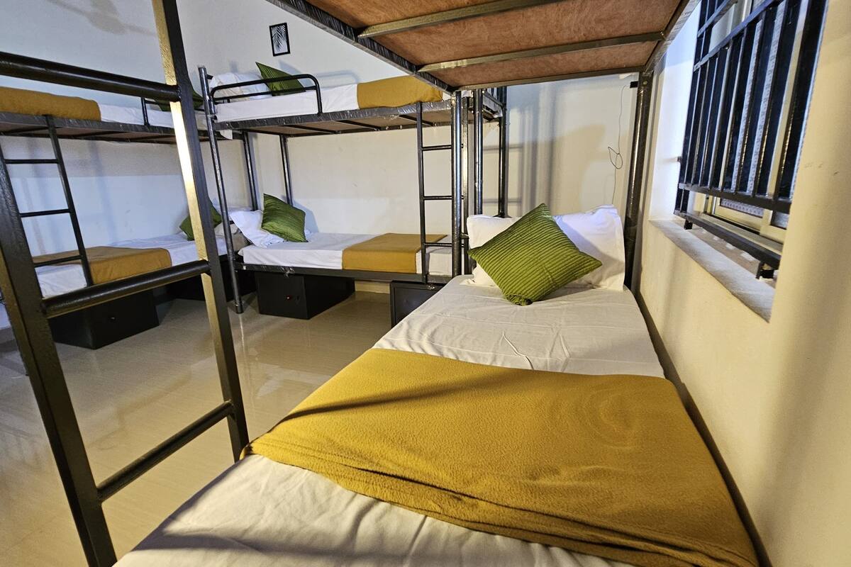 A dormitory room with bunk beds, a window with bars, and a small picture on the wall.
