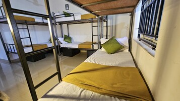 Un dormitorio con literas, una ventana con barrotes y un pequeño cuadro en la pared.