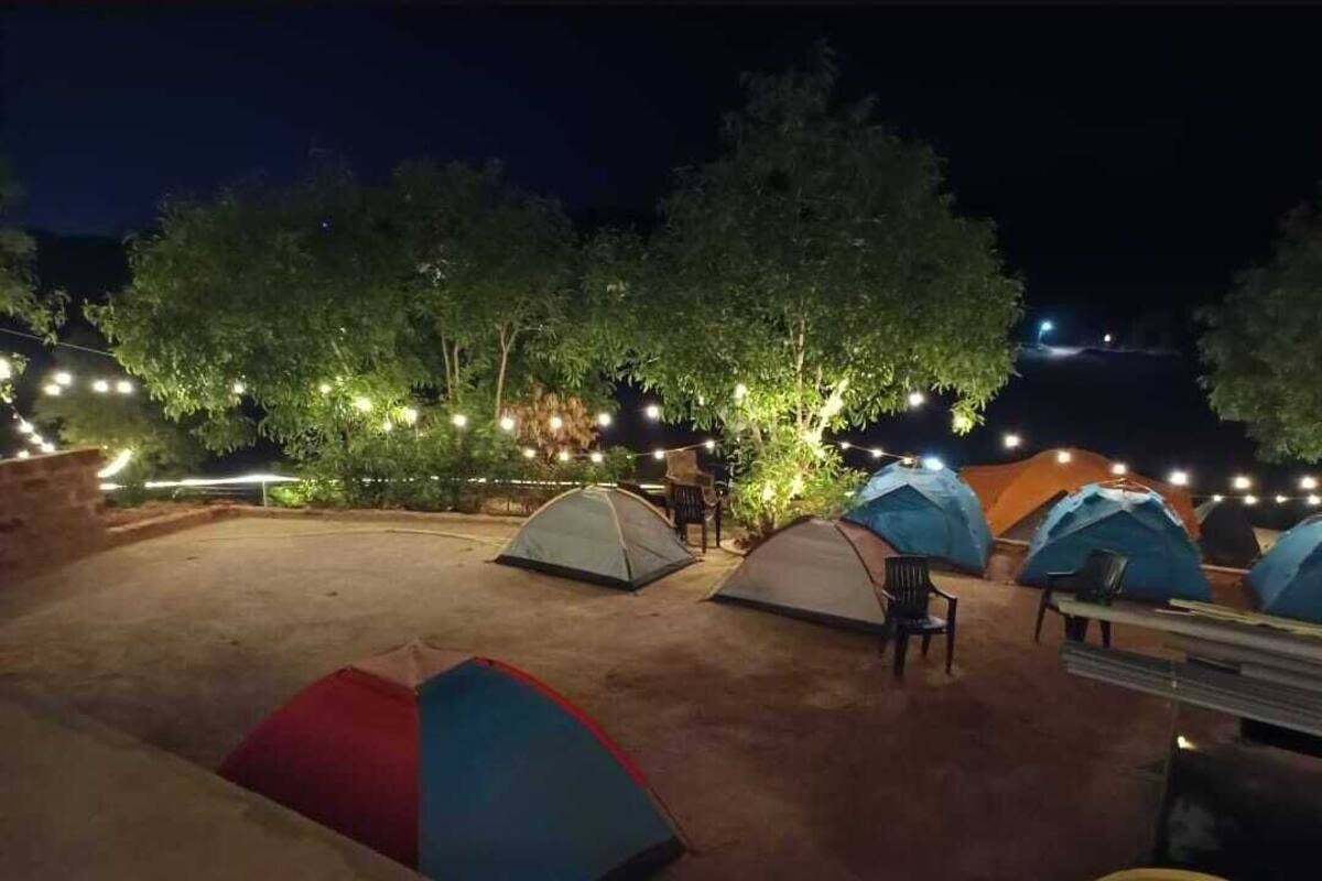 A campsite at night with several tents and string lights.