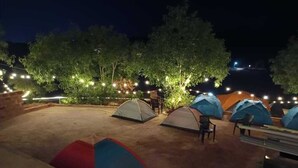A campsite at night with several tents and string lights. - Aaroha Hill Top (Gokarna)