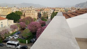 A long, straight corridor with a view of a cityscape and mountains in the distance. - Rooftop mansion (Palermo)