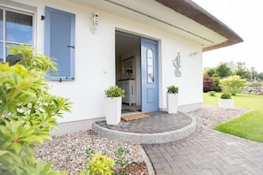 A house with a blue door, white walls, and a garden with potted plants. - Vacation home Haubenlerche 15 - Holiday home Haubenlerche 15 - Close to nature (Fuhlendorf)