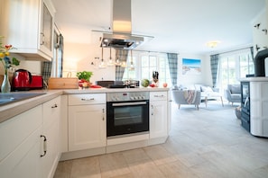 A modern kitchen with white cabinetry, a built-in oven, and a dining area with a table and chairs.