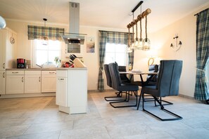 Une cuisine moderne avec des meubles blancs, un îlot central et un coin repas comprenant une table et des chaises.