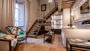A spacious living room with a staircase, a sofa, a coffee table, and a bookshelf. - Beautiful apartment for 4 guests with WIFI, A/C and panoramic view (Cortona)